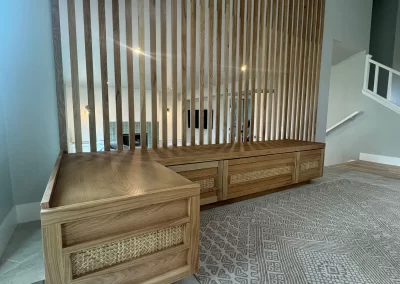 Wooden bench and slatted wall with drawers, adjacent to a patterned rug on a tiled floor, reflecting the meticulous work of skilled interior painters.