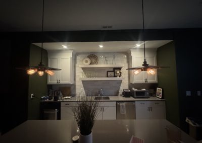 Modern kitchen with white cabinets, pendant lights, and a plant on a white island countertop.