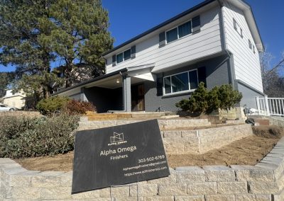 Two-story house with a sign in front for Alpha Omega Finishers, a construction and remodeling company.