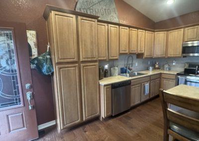 A kitchen with wooden cabinets, stainless steel appliances, and a brown door on the left.