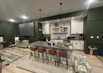 Modern kitchen with green walls, island seating, and various household items on counters and floors.