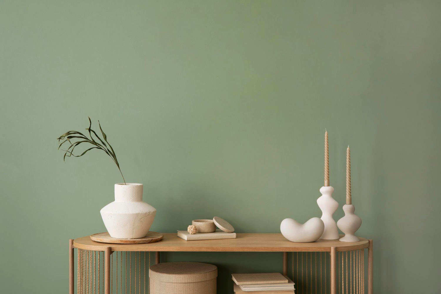 8330 Minimalist wooden console with decorative vases, candles, and baskets against a muted green wall.