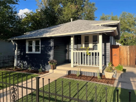 Dark blue, single-story house with a white front porch and the address 4404 above the door.