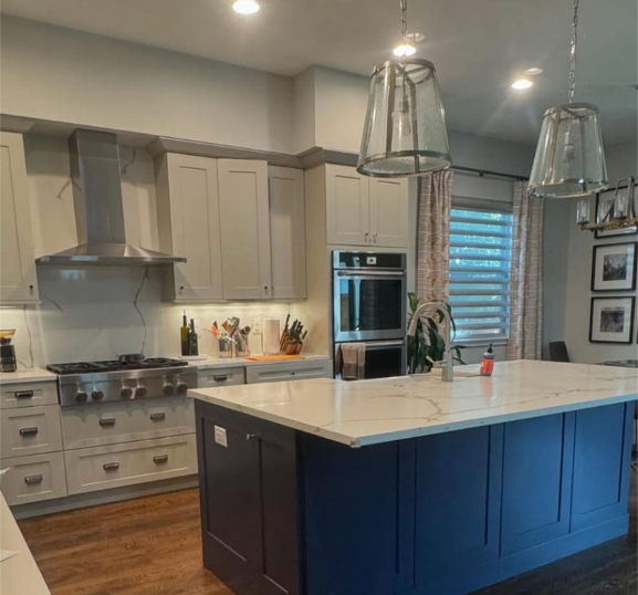 Modern kitchen with white upper cabinets, a blue center island, and stainless steel appliances.
